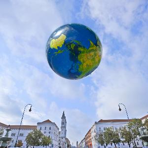 Ball einer Weltkugel schwebt über dem Hauptgebäude der LMU