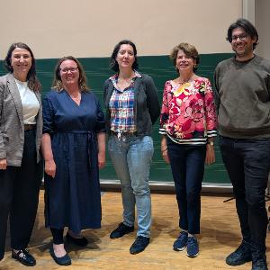 Several people are standing in a group in front of a blackboard
