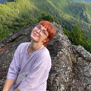 A student smiles into the camera in front of a mountain range