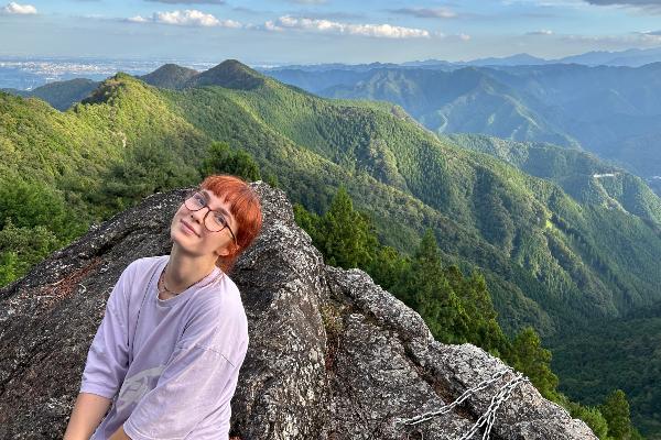 A student smiles into the camera in front of a mountain range