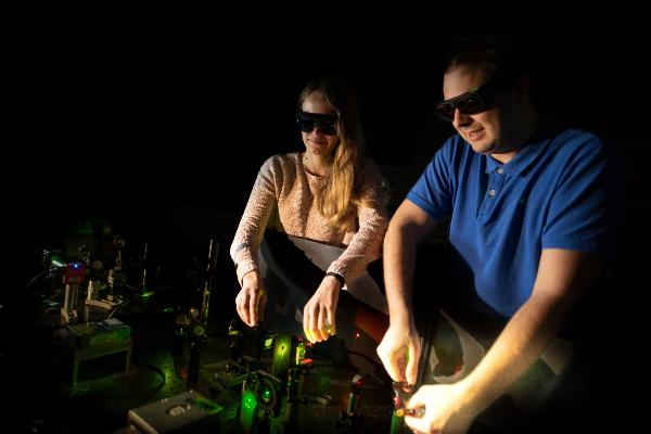 Fiona Cole und Jonas Zähringer justieren ein auf einem Lasertisch stehendes Fluoreszenzmikroskop.