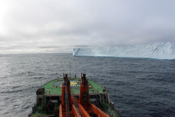 Research ship in front of an iceberg in the Southern Ocean