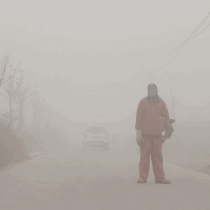 Mann steht kaum sichtbar im Smog