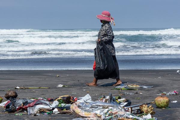 Frau sammelt Plastik am Strand