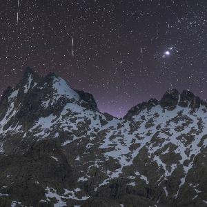 Berge vor Nachthimmel mit Sternen und Sternschnuppen