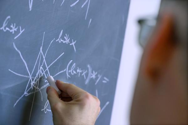 Close-up of a green board on which a calculation is written in chalk