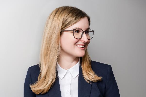 Porträt von Prof. Katja Weidner, Professorin für Lateinische Philologie, im dunkelblauen Anzug und mit Brille.