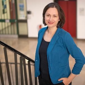 Professor Mirjana Sakradzija is standing in the stairwell of the building on Luisenstraße. She is looking at the camera with her left hand half in her trouser pocket.